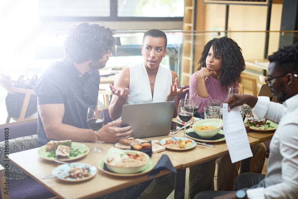 A group of businesspeople talks about the project in a restaurant at the dinner table.