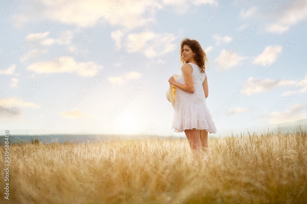 Woman in hat on the field with flowers on the field background Woman in hat on the field with flowers on the field background