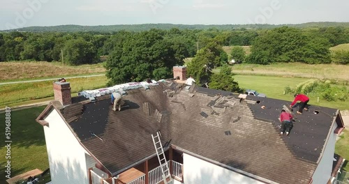 Drone Gliding Slowly Towards Roofers Halfway Done Removing Shingles