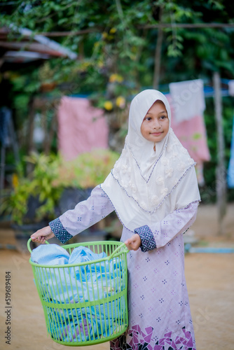 Islamic girls put clothes to dry in a basket.
