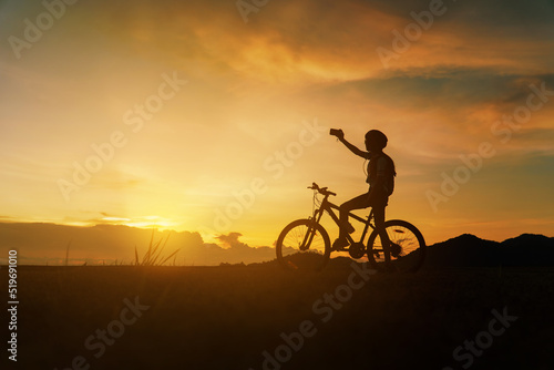 Silhouette of woman riding bicycle at sunset, cheerfully at the end of the day Fototapet