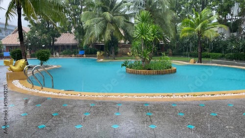 Wallpaper Mural Downpour by resort swimming pool surrounded by trees. Monsoon, wet season in Thailand concepts Torontodigital.ca