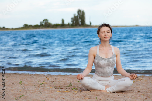 Woman practicing yoga outside in lotus pose on beach