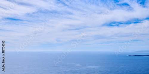 Beautiful  calm and quiet view of the ocean and clouds in blue sky with a small tropical island and copy space background. Landscape of a cloudy atmosphere and climate in a natural ocean environment