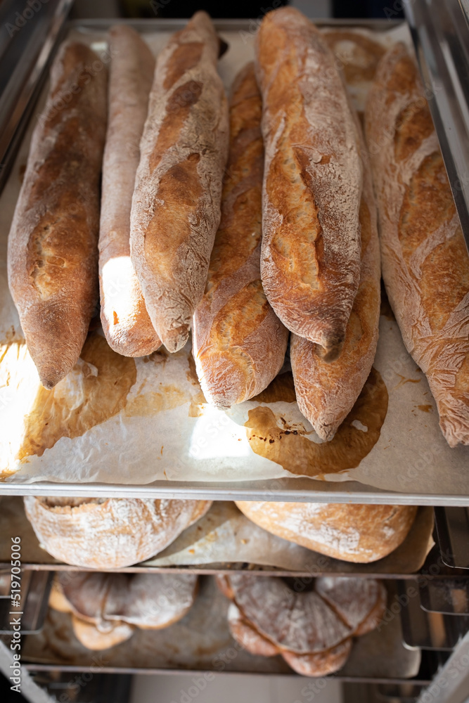 Finished French bread in the bakery on the racks. Baguettes, rustic bread, crown of kings Bordeaux. Vertical photo.