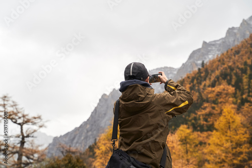 asian tourist taking a landscape picture using cellphone