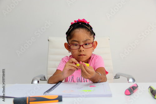 4-year-old brunette Latina girl with autism spectrum disorder ASD like Asperger, Rett and Heller draws at a desk, plays with colors alone antisocial
 photo