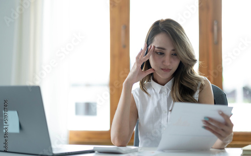 Image of an Asian woman who is tired and overthinking from working with a tablet at the office.