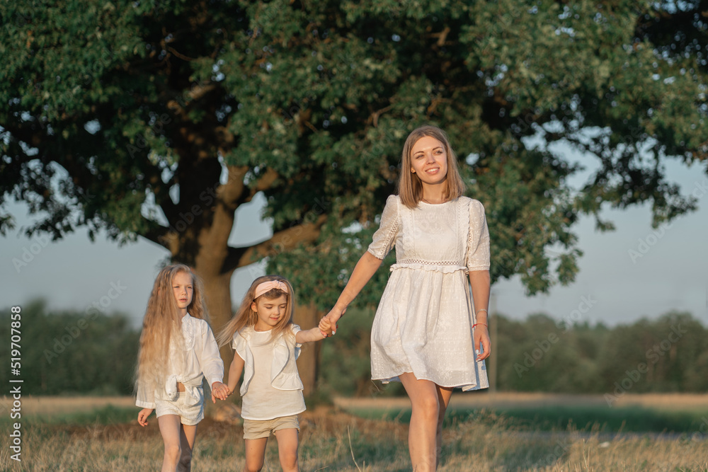 Harmonious relationship of mother with children. World Women's Day. Mom walks with the children in the village. Girls in a white dress with blonde hair