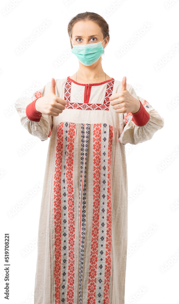 A woman in a Russian folk costume and medical mask shows the class with two hands, looks at the camera. Russian beauty. a girl from the province. protect yourself and your family. isolated