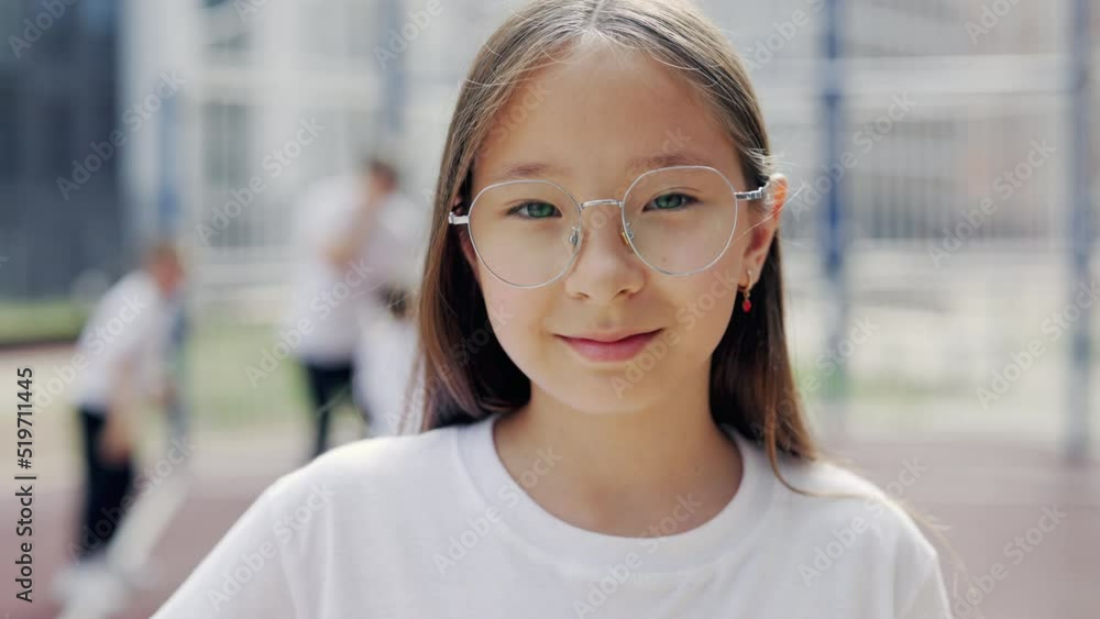 Portrait of little asian schoolgirl in glasses attending a sport classes outdoor with coach looking at camera. Sport, education and happy childhood concept. Portrait of little asian schoolgirl in glasses attending a sport classes outdoor with coach looking at camera. Sport, education and happy childhood concept.