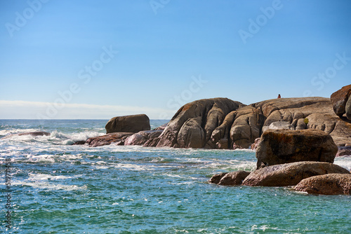 Big boulders, rocks and stones at the beach, sea and ocean against a clear blue sky background with copy space. Calm, majestic and scenic landscape view across the horizon and rocky coast in summer