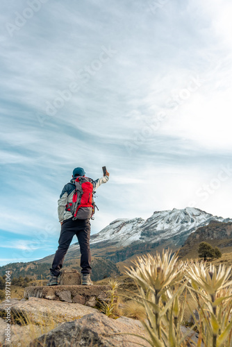 Young man taking a selfie with mobile smart phone hiking mountains