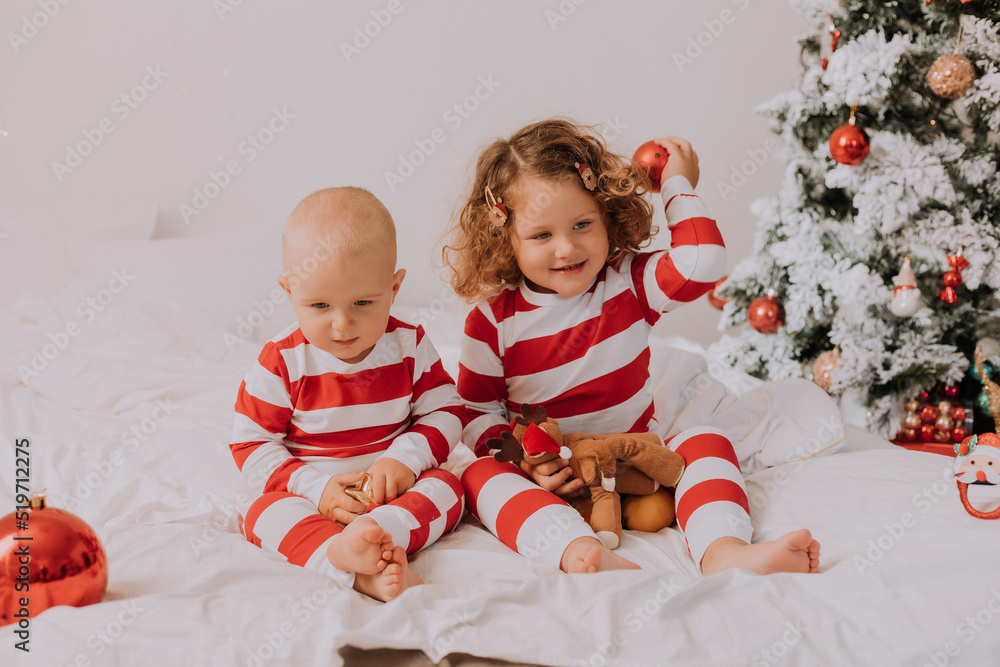 children in red and white pajamas play, have fun, make faces in bed. lifestyle children in red and white pajamas play, have fun, make faces in bed. lifestyle