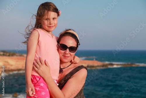 Happy mother with smiling little daughter are on a beach