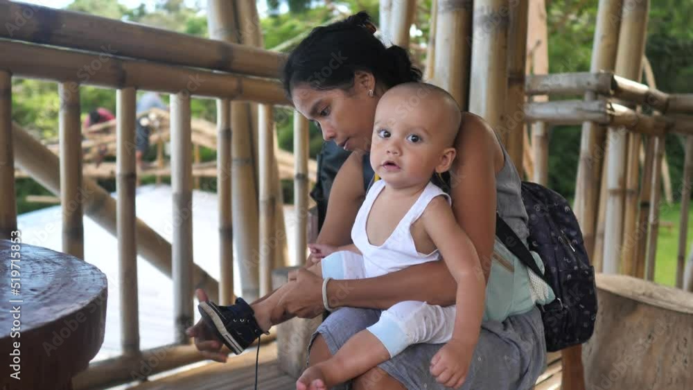 Mother helps put shoes on her baby toddler sitting on her lap. Mother helps put shoes on her baby toddler sitting on her lap.