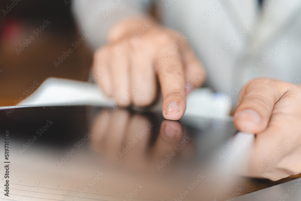Fototapeta premium Hands of young man typing and working on digital tablet with financial and sales chart