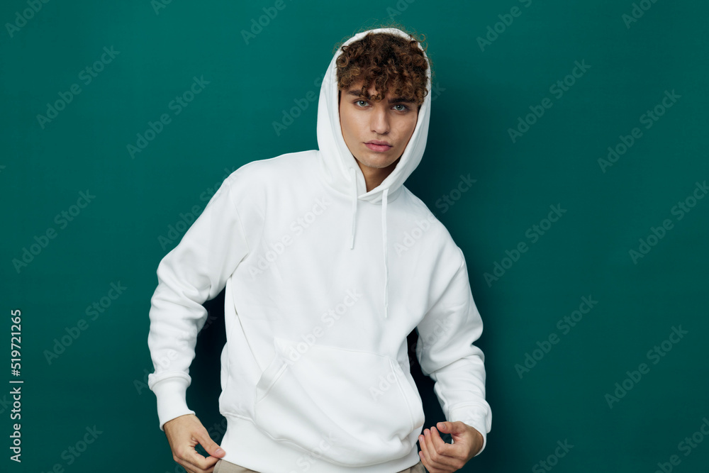 a handsome man stands on a green background in a white hoodie and poses relaxed looking at the camera with a slight smile on his face. Horizontal Studio Photography a handsome man stands on a green background in a white hoodie and poses relaxed looking at the camera with a slight smile on his face. Horizontal Studio Photography