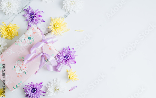 Flowers composition with white  purple and yellow chrysanthemum flowers and gift box on white marble background.