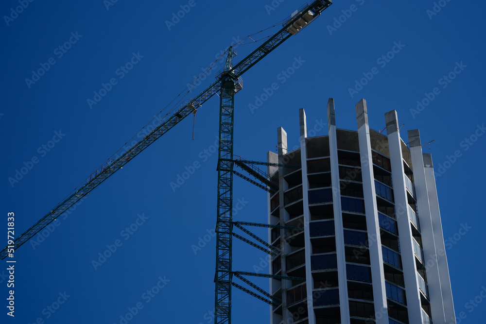 Tower crane in action construction of a new round shaped multi-storey building Tower crane in action construction of a new round shaped multi-storey building