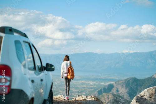 Rear view woman traveler enjoying mountain landscape, reaching summit destination on road trip