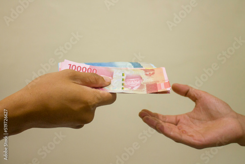 Closeup hands giving money isolated on brown background. A financial transaction between two parties