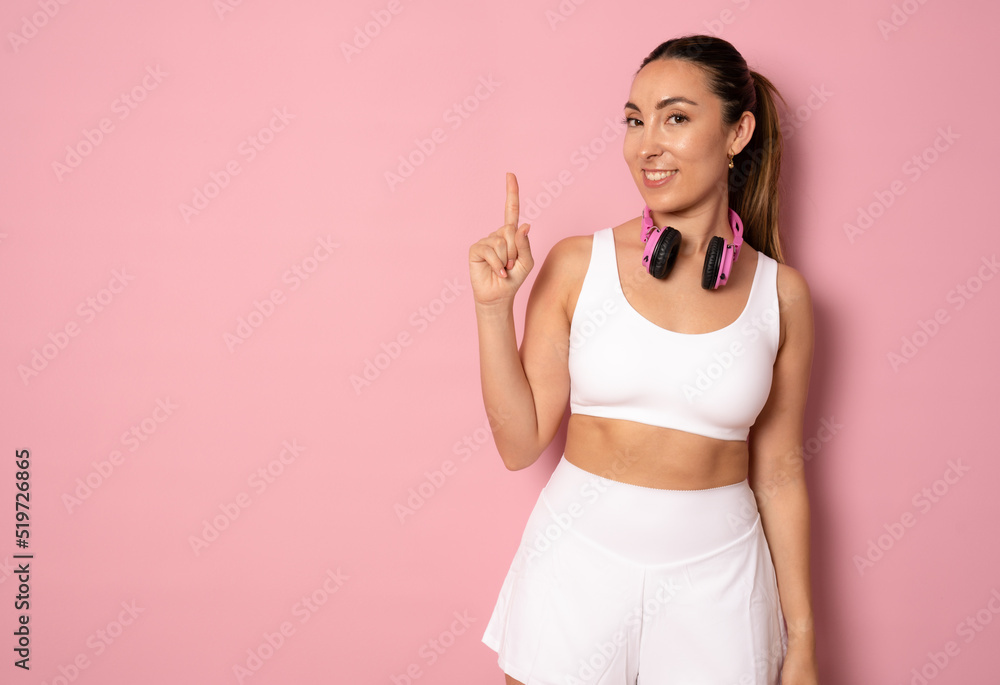 Photo of happy good mood smiling cheerful sportive athlete woman pointing finger up standing isolated on pink background Photo of happy good mood smiling cheerful sportive athlete woman pointing finger up standing isolated on pink background