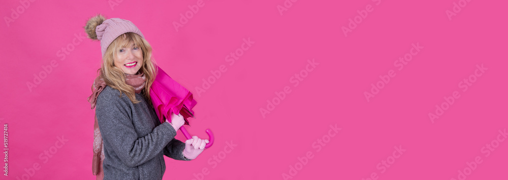Fototapeta premium mature smiling woman with umbrella on pink background