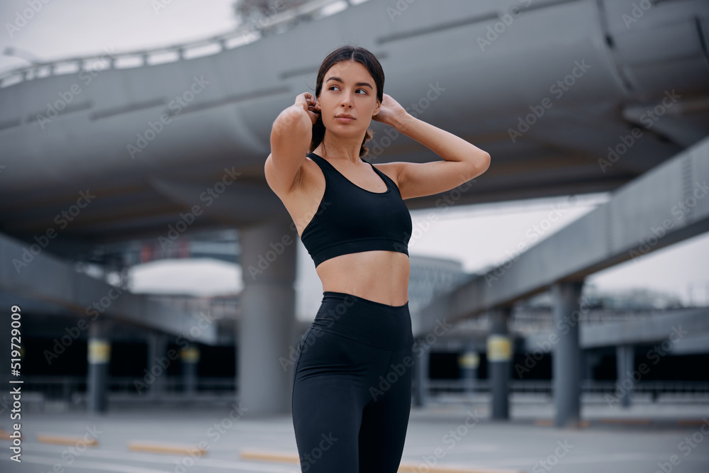 Obraz premium Pretty brunette woman fixes her hair after workout