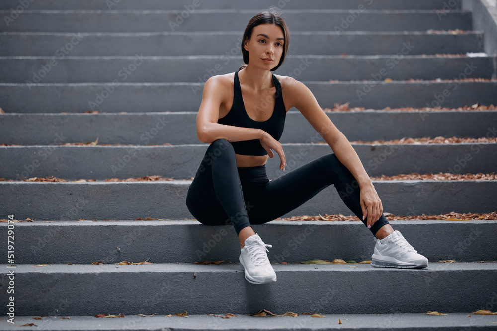 Woman sitting on the stairs outdoors, resting after nice workout session Woman sitting on the stairs outdoors, resting after nice workout session