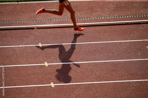 陸上競技場で走る女子選手の影 photo