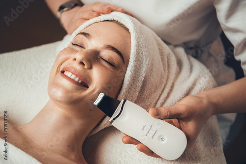 Close up photo of a woman in cosmetological clinic getting ultrasonic peeling face procedure. Medical treatment. Girl facial treatment. photo