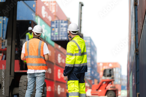 Dock manager and engineer worker discuss on quality at container shipping yard during truck lifting cargo box. Import and export product. Manufacturing transportation and global business concept