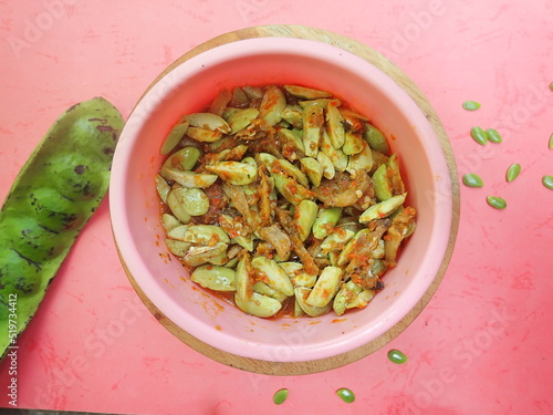 Homemade Indonesian traditional food chilli sauce parkia speciosa (sambal petai) in in a pink bowl on a red background. photo