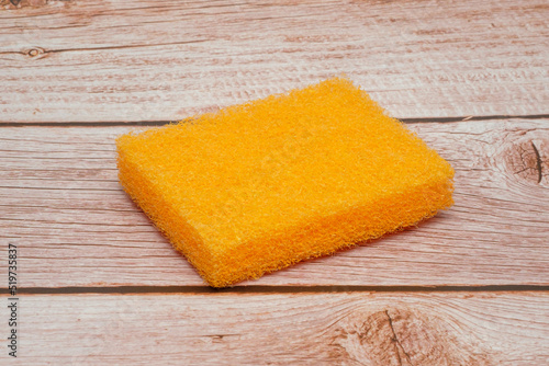 Orange scouring sponge with wood background