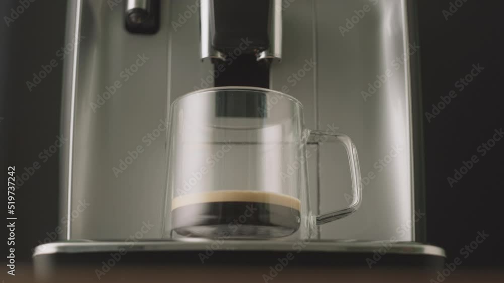 Freshly brewed coffee is poured from the coffee machine into glass cups. Freshly brewed coffee is poured from the coffee machine into glass cups.
