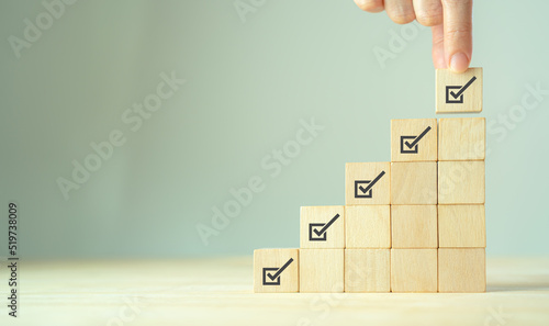 Corporate regulatory and compliance. Quality control management, ISO certification. Product, service quality warranty. Checklist survey and assessment process. Wooden cube with check mark icon.