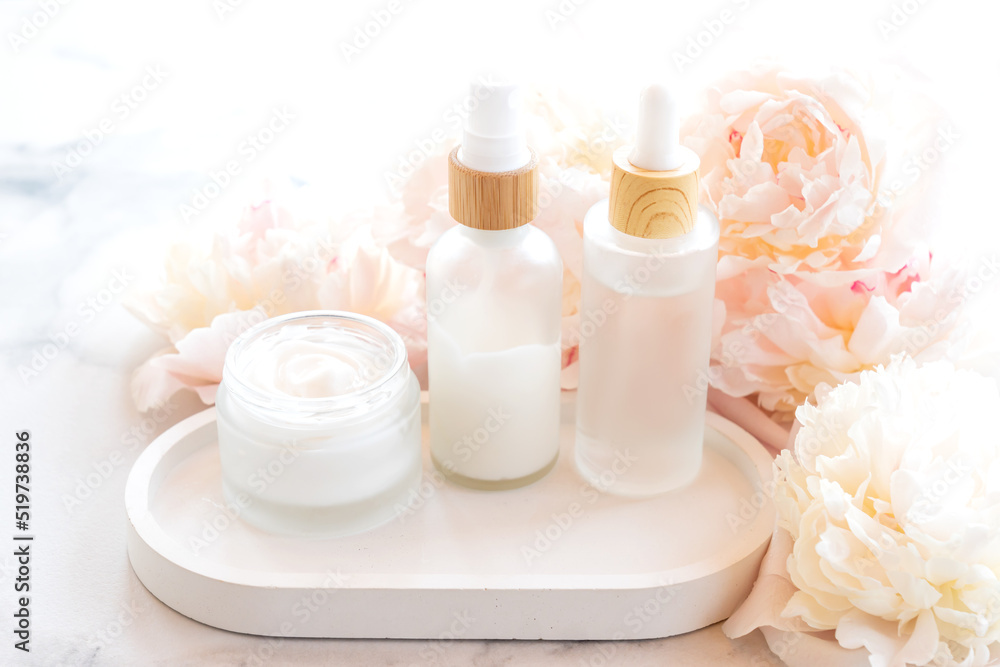 composition with cosmetic products, mockup white jars and bottles and white peonies on a marble background