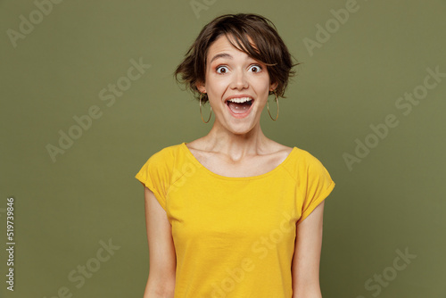 Young shocked surprised astonished woman she 20s wear yellow t-shirt look camera with opened mouth scream shout isolated on plain olive green khaki background studio portrait People lifestyle concept
