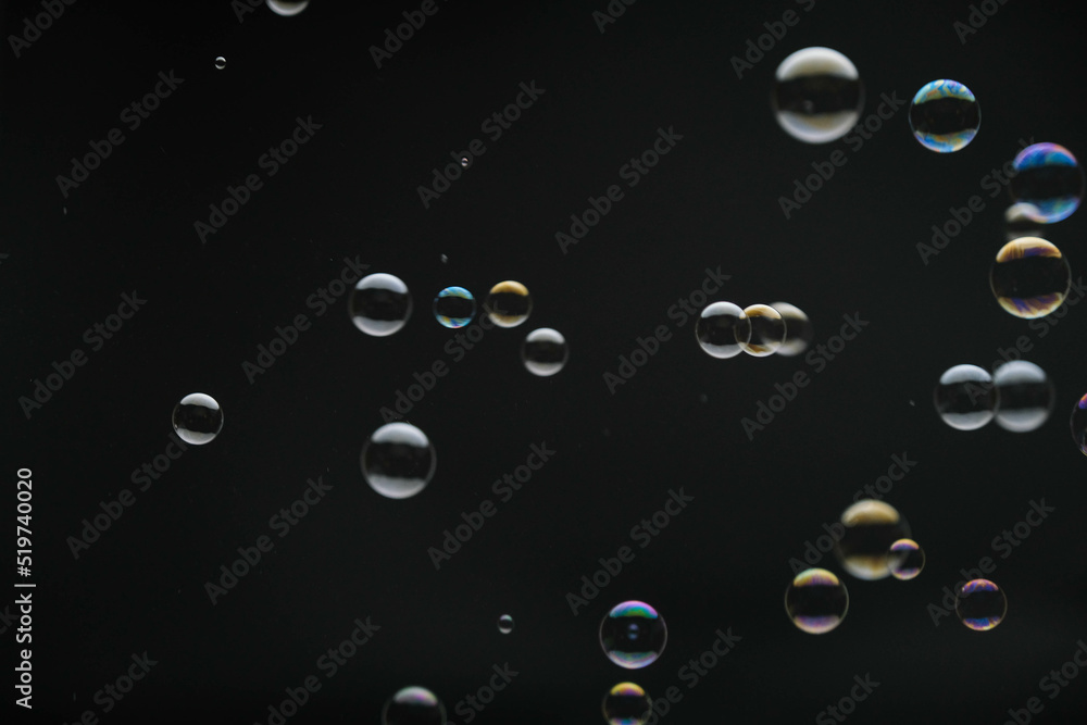 Flying soap bubbles on black background. Abstract soap bubbles with colorful reflections. Soap bubbles in motion background. Flying soap bubbles on black background. Abstract soap bubbles with colorful reflections. Soap bubbles in motion background.