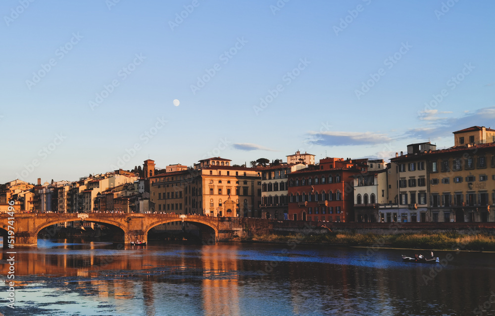Bridge over the Arno river in Florence, with many tourists waiting for the sunset. The moon is already in the sky.