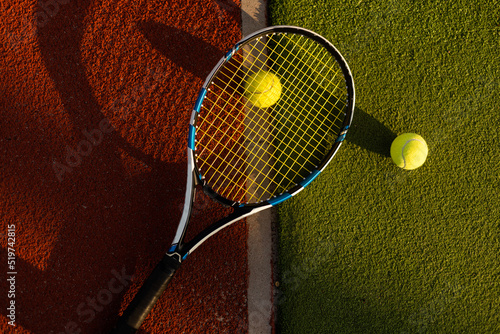 A tennis racket and new tennis ball on a freshly painted tennis court. © Angelov