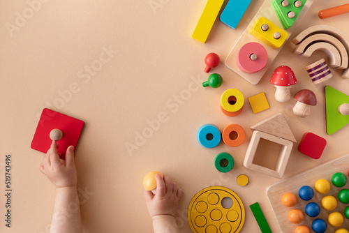 Toddler activity for motor and sensory development. Baby hands with colorful wooden toys on table top view. photo