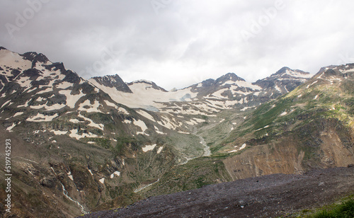 Panoramic landscape - silhouette of the top of a high mountain with glaciers and white snow and cloudy blue sky in the Elbrus region in the northern Caucasus in Russia