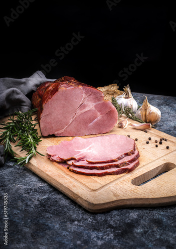 Smoked ham sliced on a wooden cutting board. Composition with Polish pork meat cold cuts, meat products.