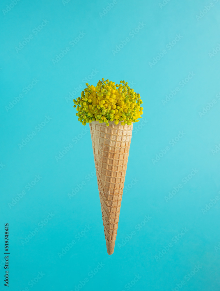 Ice cream cone with small yellow and green flowers on a light blue background.