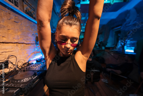 фотографія Beautiful female DJ dancing to techno in a small club