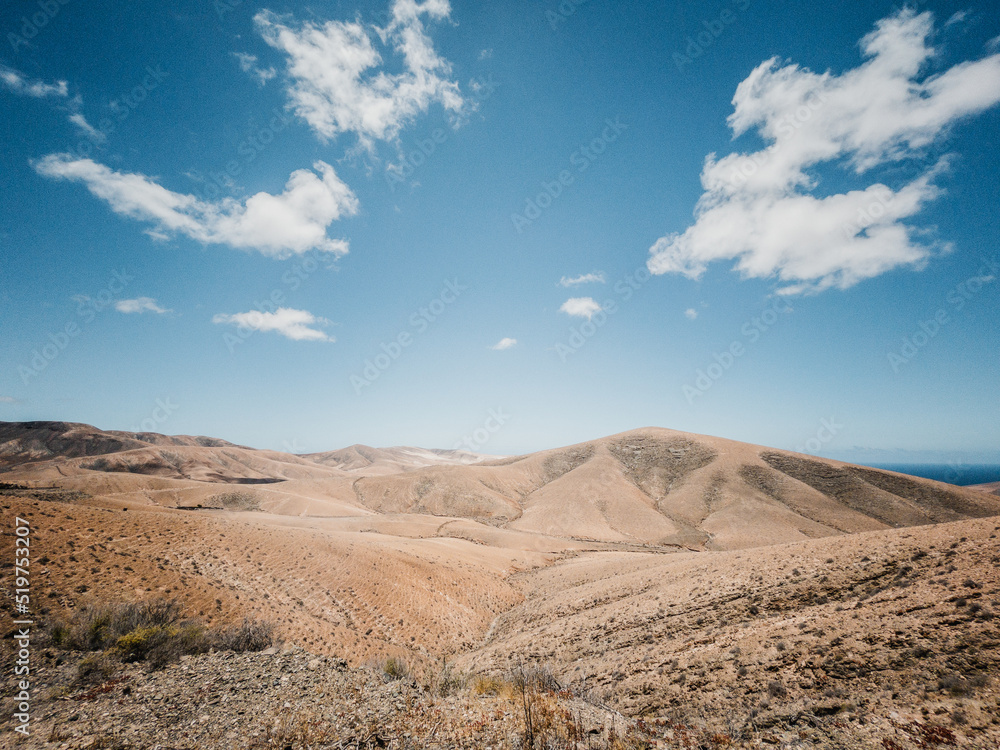 dry valley with dry grass under blue sky with clouds