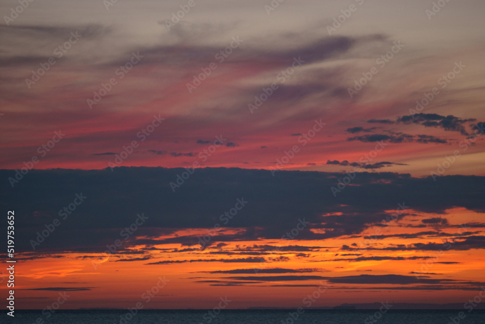 colorful dramatic red sky with cloud in the twilight after sunset over the ocean