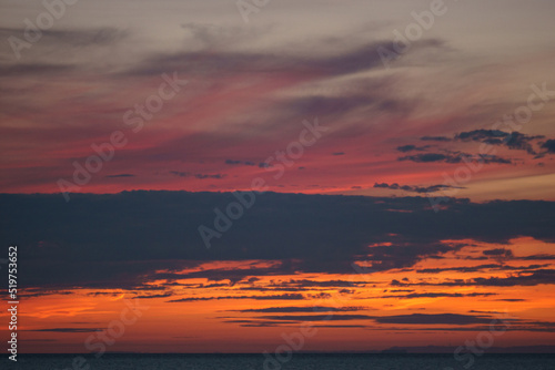 colorful dramatic red sky with cloud in the twilight after sunset over the ocean